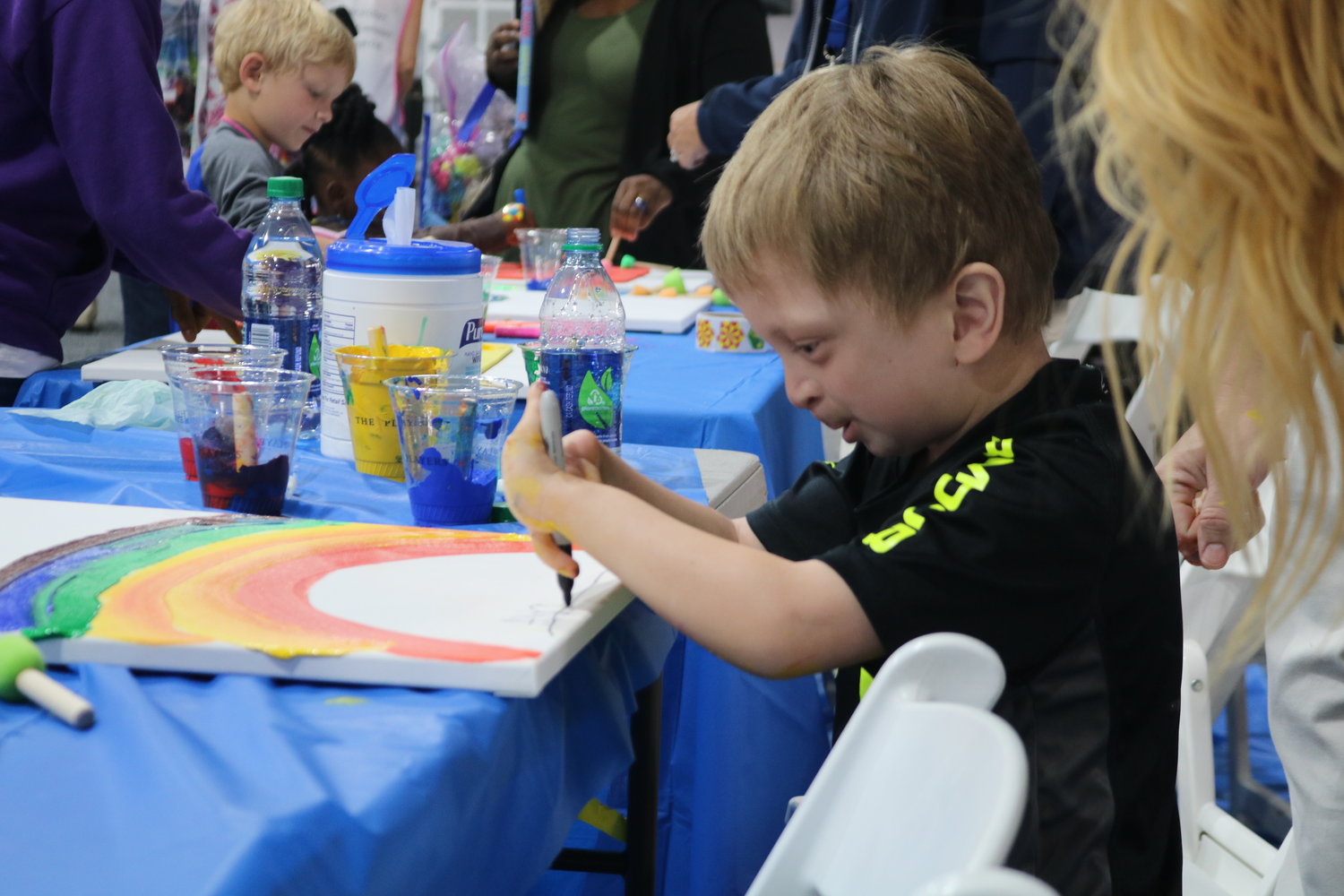 A kid at the event enjoys painting at an arts and crafts station.